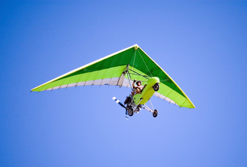 Airborne Motorized Ultralight Glider in a cloudless blue sky