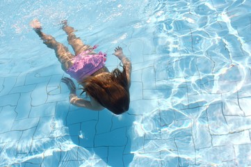 Girl swimming under water in pool