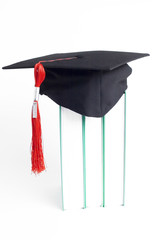 graduation cap with a red tassel on books on white background