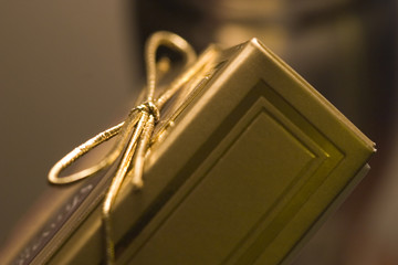 A gold color gift box with matching ribbon tie