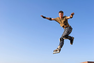 Fototapeta na wymiar Roller boy jumping from parapet on the blue sky