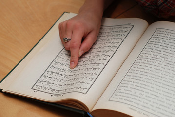 Naklejka premium Close up of girl's finger on Quran