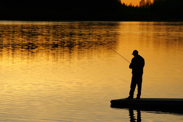 A silhouette of a fisherman as the sunset on lower.