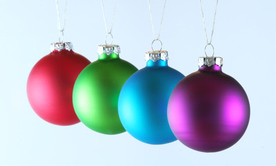 Row of four Christmas ornaments  on white background.