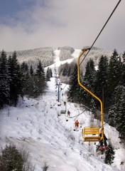 Snow landscape with cableway and skiers