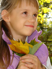 Beautiful young girl with golden leaves in her hands