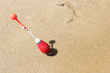 Fototapeta na wymiar a fishing float sticked into the sand of the shore