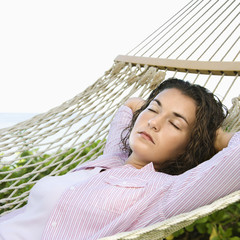 Female lying in hammock with arms behind head sleeping.