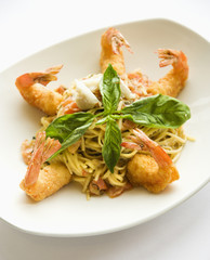 Gourmet meal with fried shrimp and pasta garnished with basil.