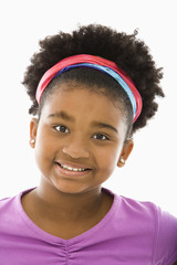 African American girl wearing headband smiling at viewer.