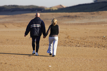 couple qui marche en se tenant la main sur la plage