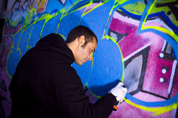 urban lifestyle: young man painting on a wall