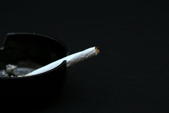 hand rolled cigarette in black ashtray against dark background