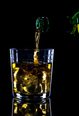 Whiskey being poured into a glass of ice.