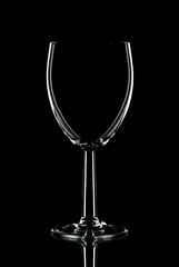 Low key shot of a single wine glass against a black background.