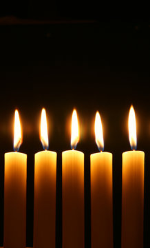 Five burning candles over black background
