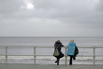 Chicas sentadas mirando el mar