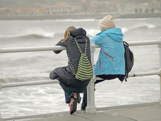 Chicas sentadas mirando el mar