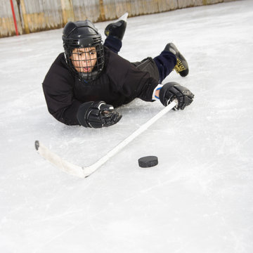 Ice hockey player boy in uniform sliding on ice.