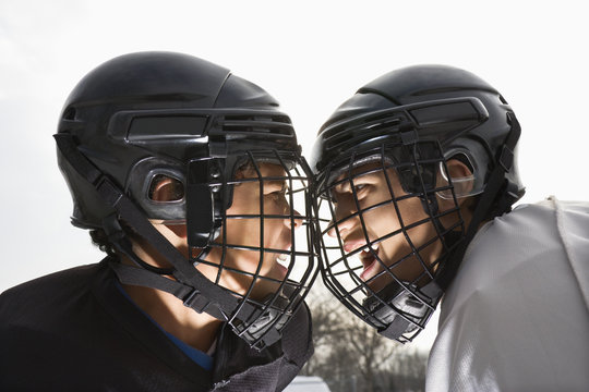 Two Ice Hockey Players In Uniform Facing Off.