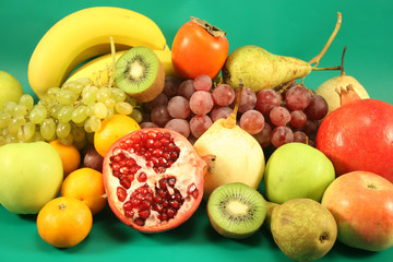 Naklejka na ściany i meble Different fruit on a green background.