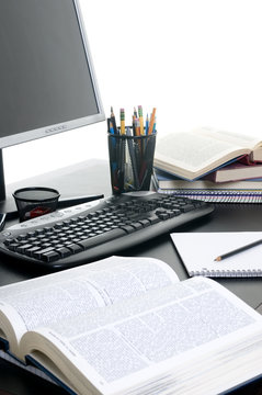 Piles of books open with a computer. research paper.