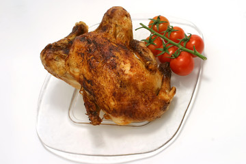 Whole fried chicken on dish with six cherry tomato on branch