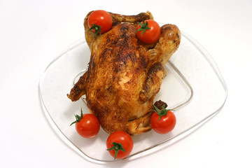 Whole fried chicken on dish with fifth cherry tomato on him