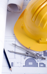 A hardhat and construction drawings on a table.