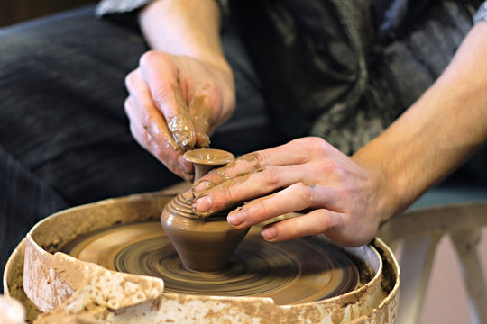 Hands of ceramist with earthenware on potter's lathe