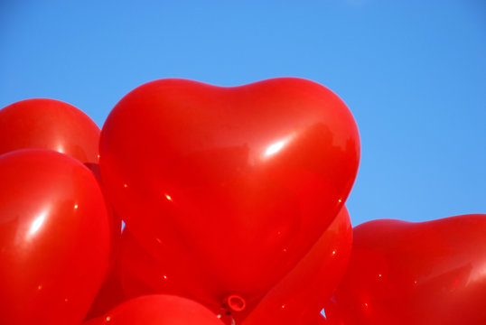 Rote Herzluftballons vor blauem Himmel