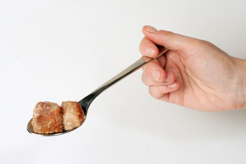 Fried meat on stainless serving spoon, on white
