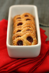 A plate of raspberry pretzel cookies with a red napkin