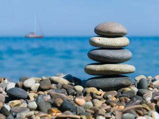 Fototapeta na wymiar Stos kamieni na plaży i jachtów w morzu