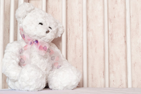 Small, white teddy bear, childish toy sitting at bed