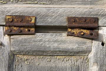 Aged wooden window with two rusty hinges