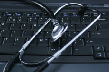 Silver sthetoscope on notebook keyboard.