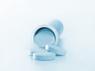 Closeup of blue tablets spilling out of phial
