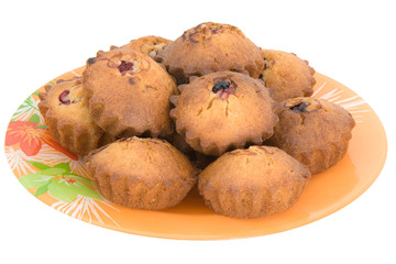 Tasty small baked cakes on orange round plate isolated on white