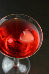 A red martini cocktail with a heart shaped ice cubes