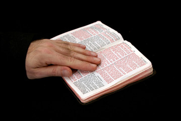hand of man resting on bible, reading the book