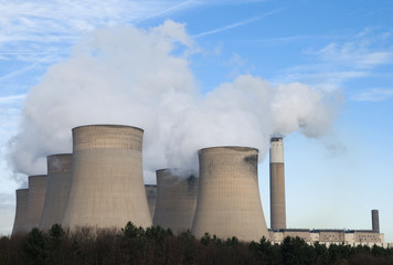 Fototapeta premium Powerstation cooling towers emitting steam against blue sky
