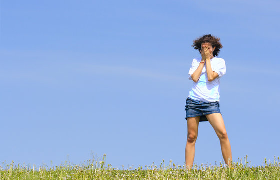 Crying teen girl against a blue sky with space for text on left