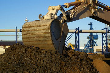 Hydraulic excavator at work. Shovel bucket against blue sky