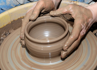 potter's wheel and hands of craftsman hold a jug