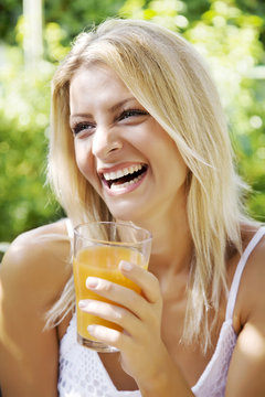 happy woman drinking her morning orange juice in her garden