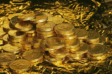 Pile of golden chocolate coins on golden background