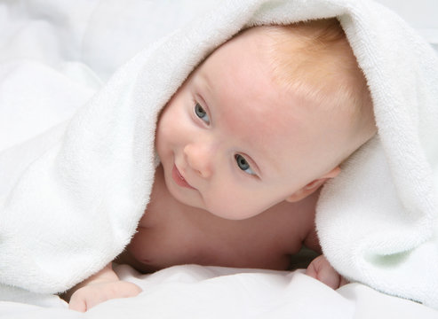 Tot under towel on white background.