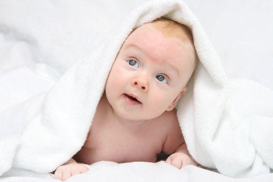 Tot under towel on white background.