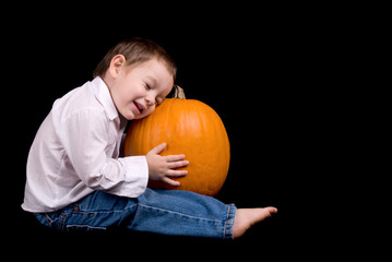 Young boy sitting and hugging a pumpkin